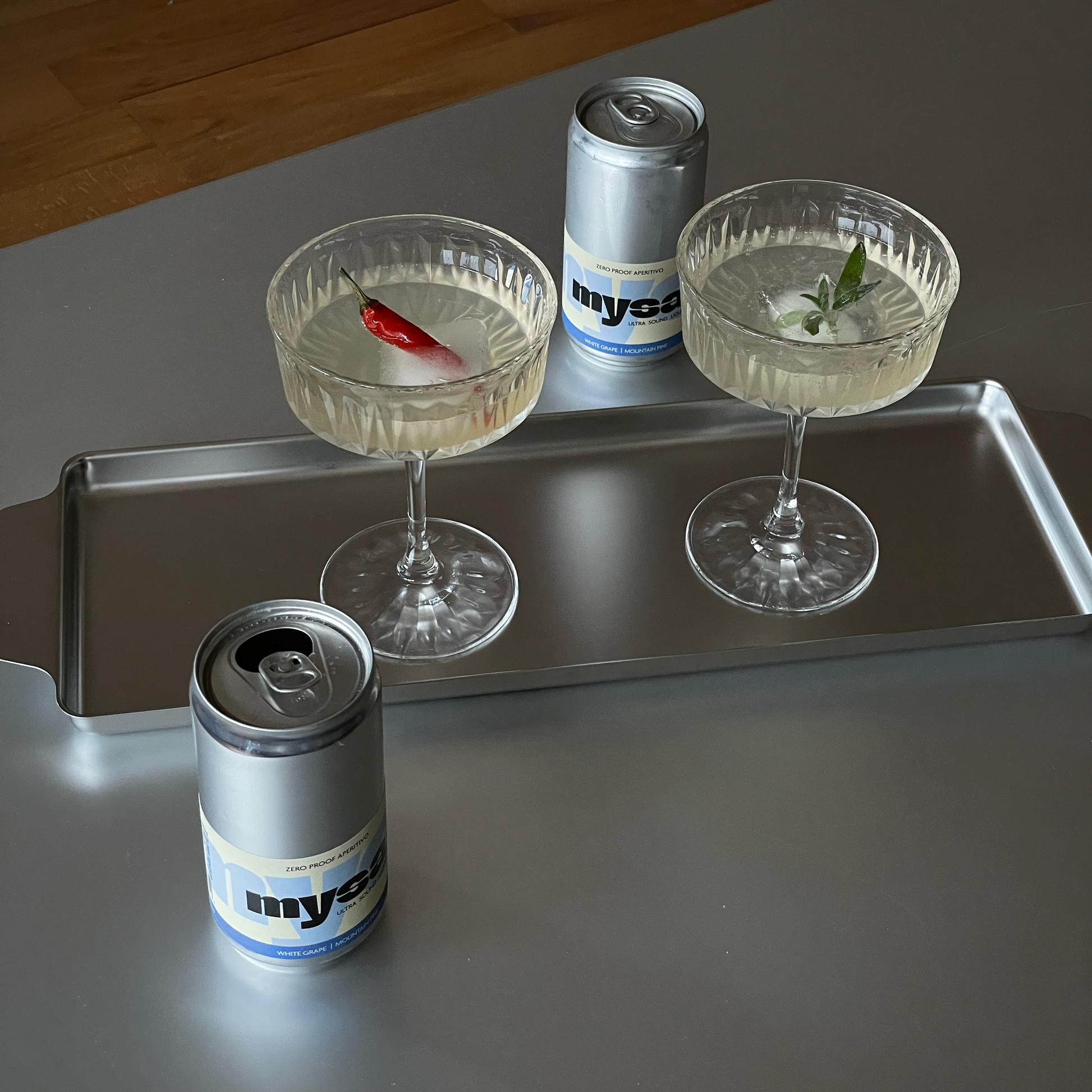 Two mysa beverages served in a coupe glass with citrus garnish on a silver table